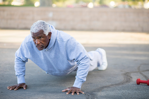 A senior African American man does pushups