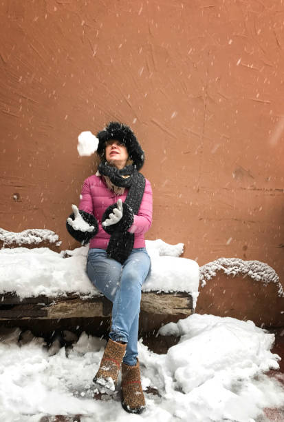 istock Snowing: Woman Sitting on Snowy Bench Throwing Snowball 675816326