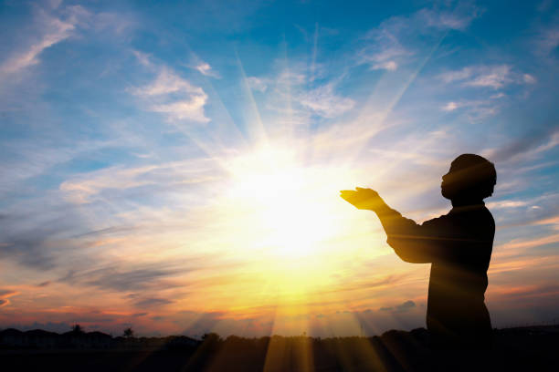 silueta de un hombre está rezando sobre fondo puesta de sol - assistance vitality spirituality religion fotografías e imágenes de stock