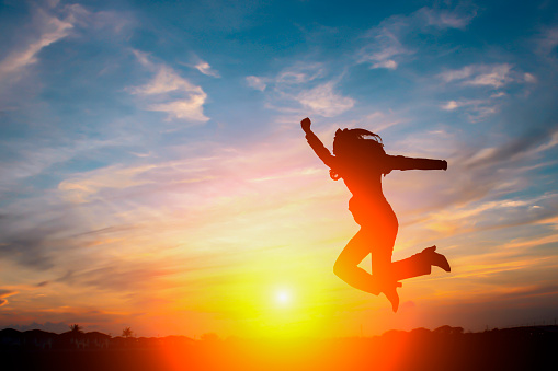 Happy business woman jumping in sunset sky