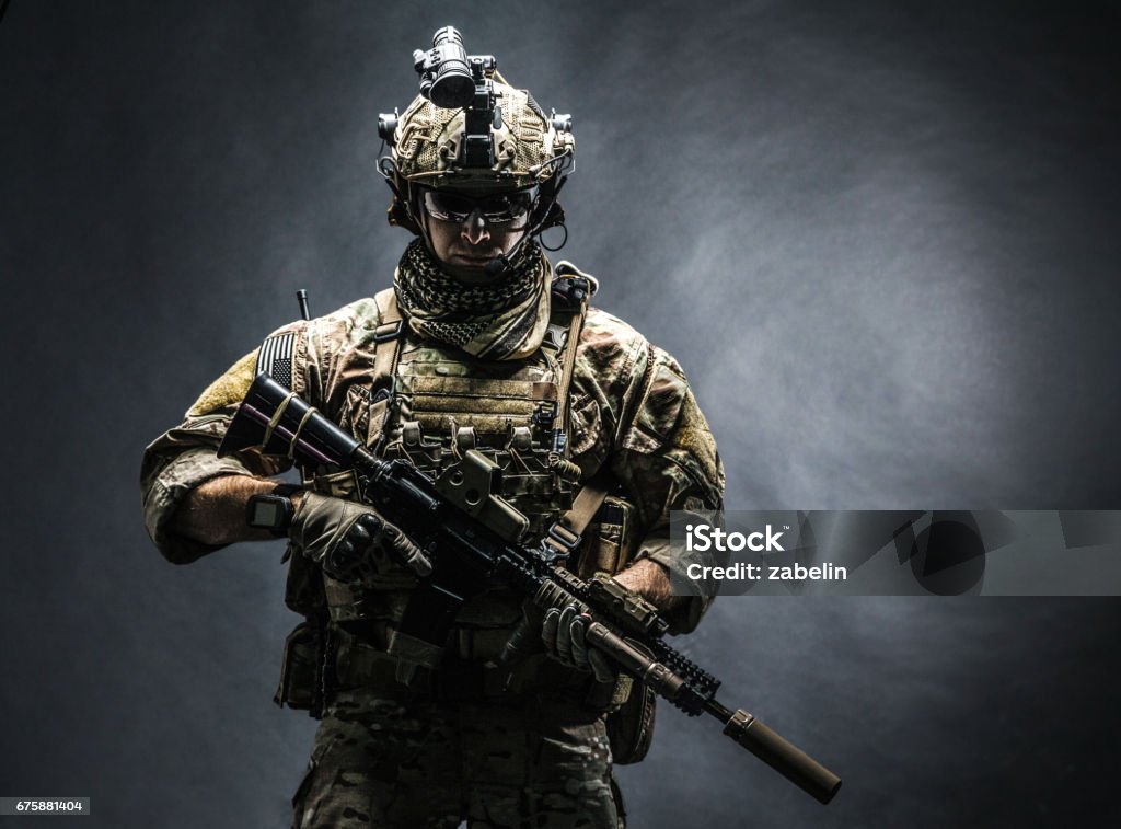 Army Ranger in field Uniforms Army soldier in Combat Uniforms with assault rifle, plate carrier and combat helmet are on, Shemagh Kufiya scarf on his neck. Studio shot, dark background Army Soldier Stock Photo