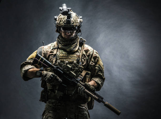 Army Ranger in field Uniforms Army soldier in Combat Uniforms with assault rifle, plate carrier and combat helmet are on, Shemagh Kufiya scarf on his neck. Studio shot, dark background soldier stock pictures, royalty-free photos & images