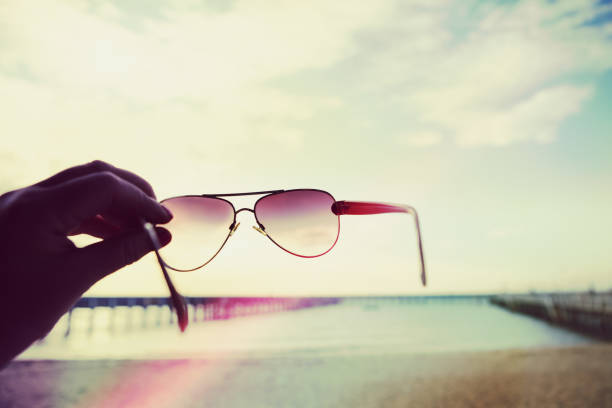Colorful light leaks on hand holding sunglasses at a beach on vacation