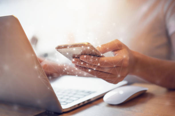 woman hand holding mobile phone and laptop data synchronization - user access imagens e fotografias de stock