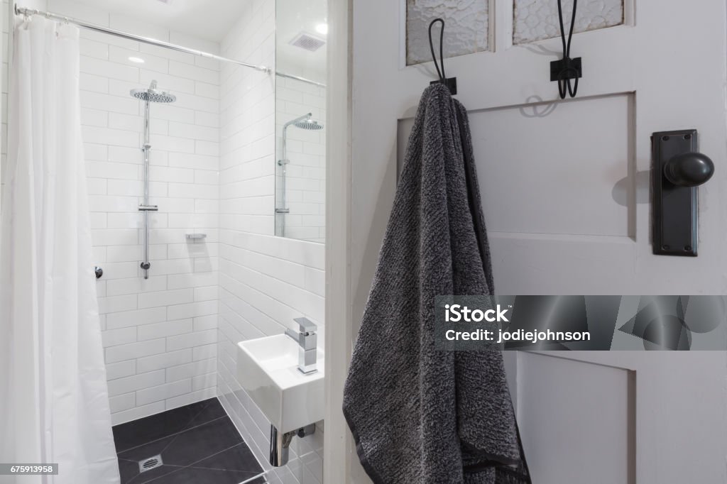 Small white tiled ensuite bathroom with shower and hanging towel Small white tiled ensuite bathroom with shower and hanging towel on a hook horizontal Bathroom Stock Photo