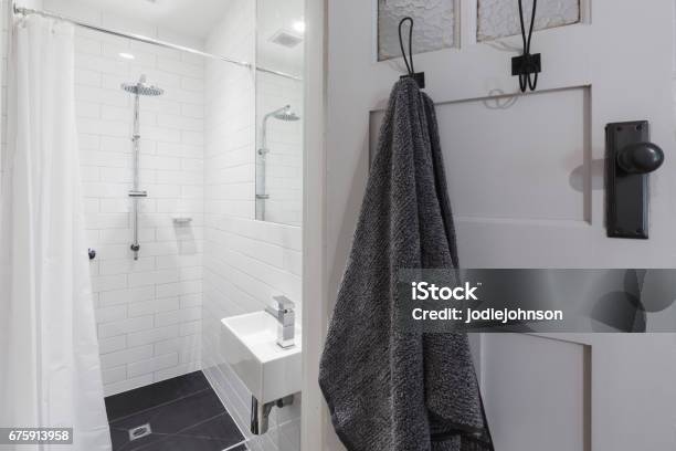 Small White Tiled Ensuite Bathroom With Shower And Hanging Towel Stock Photo - Download Image Now