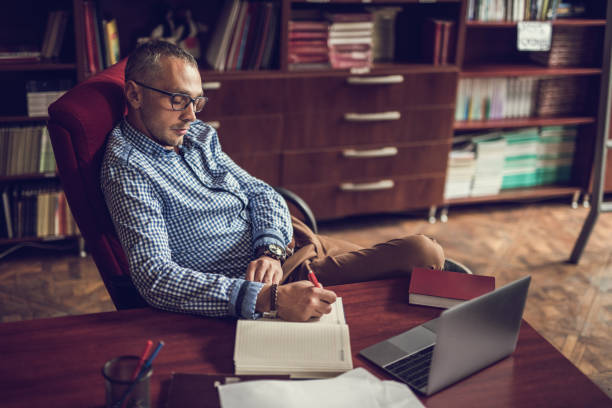 istock Businessman sitting at home office and writing something in note 675919930