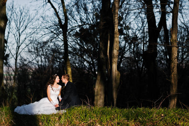 gran y hermosa pareja de bodas al atardecer cerca de madera - silhouette kissing park sunset fotografías e imágenes de stock