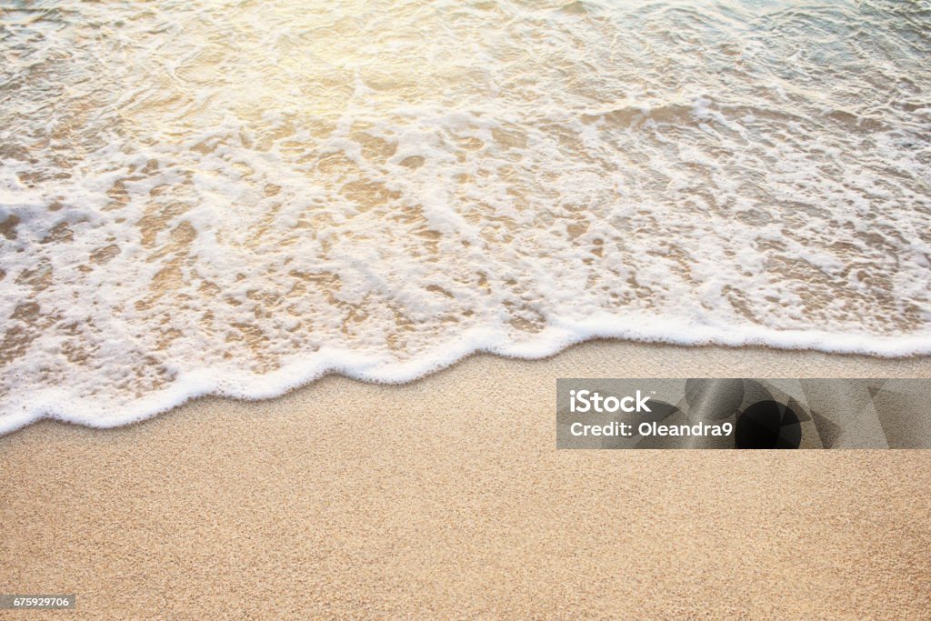 Soft wave of sea on the sandy beach Soft Wave Of Ocean On Sandy Beach At Warm Golden Sunset Light. Background. Selective focus. Beach Stock Photo
