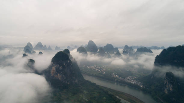 vista aérea del paisaje nuboso sobre las tierras de cultivo y la montaña - xingping fotografías e imágenes de stock