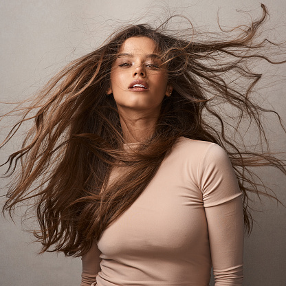 Portrait of a beautiful young woman posing with the wind in her hair in studio