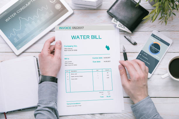 Man holds invoice of water usage over desk. stock photo