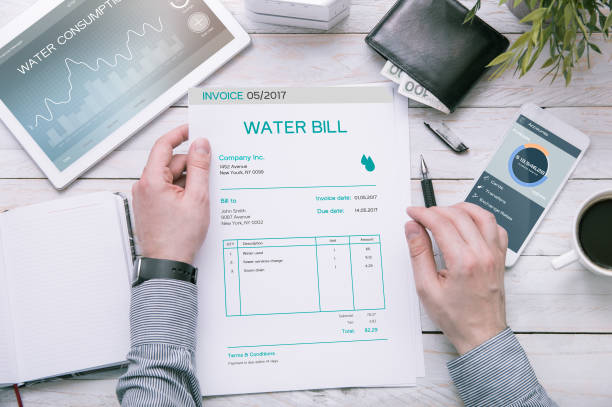 man holds invoice of water usage over desk. - usage imagens e fotografias de stock