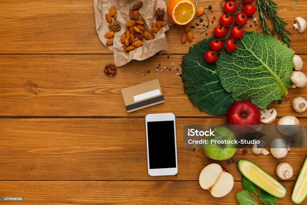 Healthy food, grocery online shopping Healthy food, grocery online shopping, copy space on mobile screen. Fresh organic vegetables and fruits on wood table, top view, flat lay Groceries Stock Photo