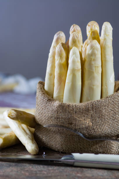 istock Spring season - fresh white asparagus in burlap sack on granite plank background 675961876