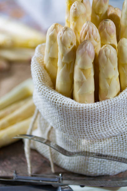 istock Spring season - fresh white asparagus in burlap sack on granite plank background 675961944