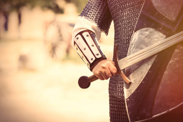 strong knight hand with beautiful sword and shield on the middle ages decoration background strong knight hand with beautiful sword and shield on the middle ages decoration background knight person photos stock pictures, royalty-free photos & images