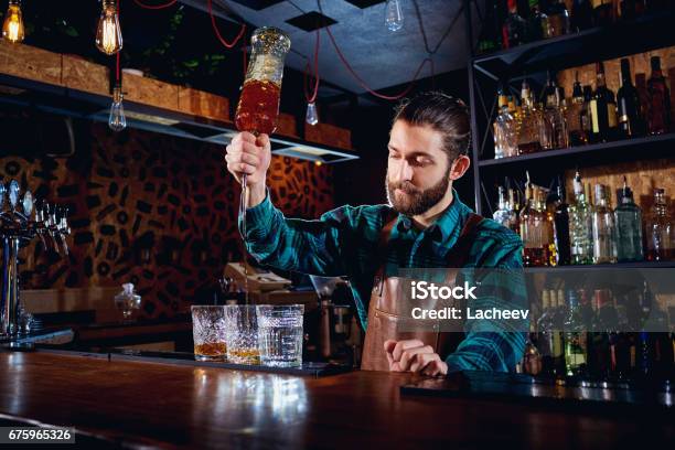 Photo libre de droit de Le Barman Avec Une Barbe Verse Lalcool Dans Les Verres Dans Un Bar banque d'images et plus d'images libres de droit de Barman