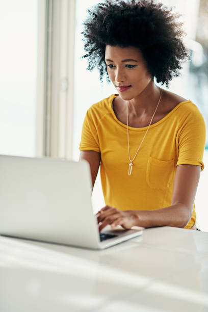 Doing a little internet surfing Cropped shot of an attractive young woman using her laptop while chilling at home the black womens expo stock pictures, royalty-free photos & images