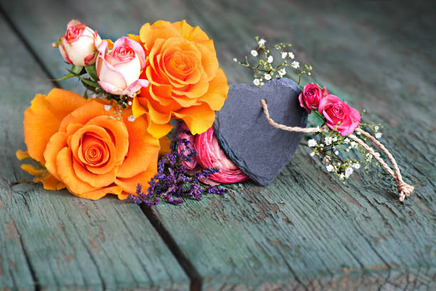 Still life with roses and a heart from slate on an old shabby wooden table for mothers day
