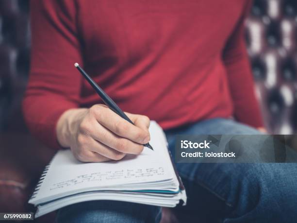 Man On Sofa Writing In Notebook Stock Photo - Download Image Now - Men, Writing - Activity, Note Pad