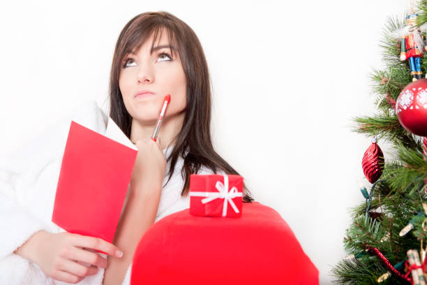 Beautiful woman thinking while writing a Christmas card