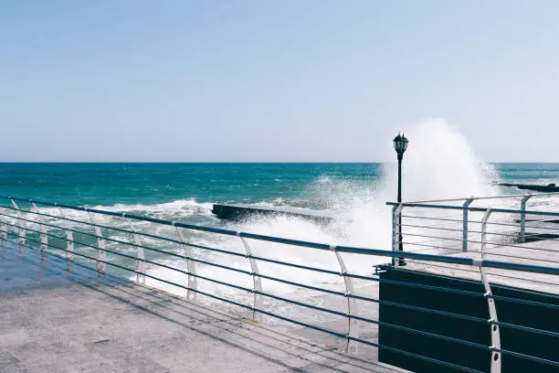 Photo of Waves break on the pier on a sunny day