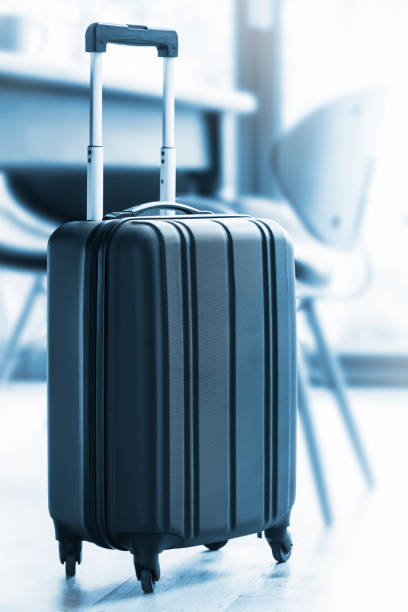 istock A modern, black wheeled suitcase beside a table and chairs 675997448