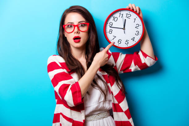 schöne junge frau mit uhr stand vor wunderbar blauem hintergrund überrascht - ethnic small fashion model one person stock-fotos und bilder