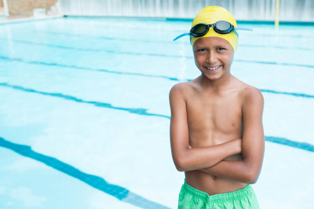 istock Smiling boy standing with arms crossed near poolside 676019830