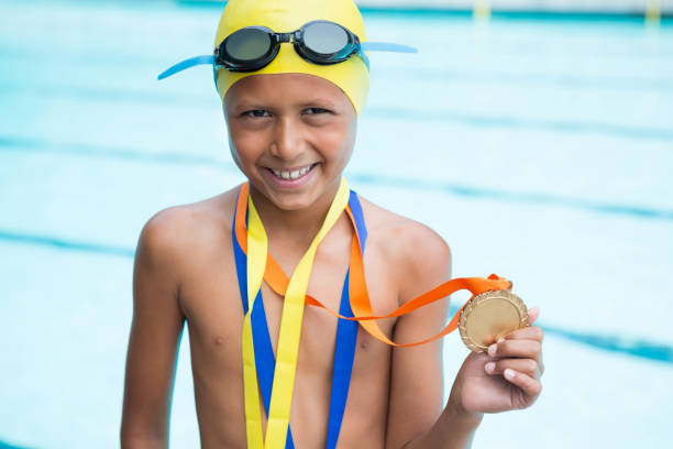 istock Boy with gold medals around his neck standing near poolside 676019950