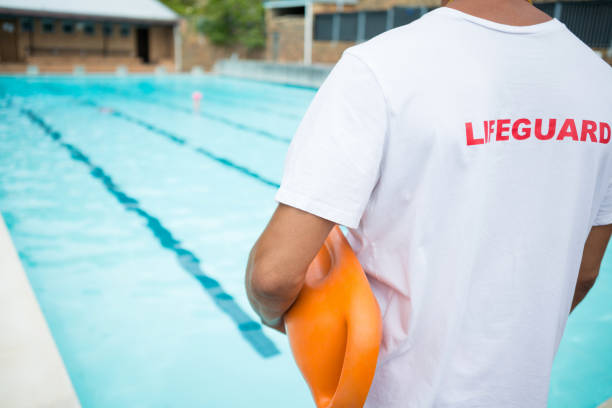istock Lifeguard standing with rescue buoy near poolside 676022664