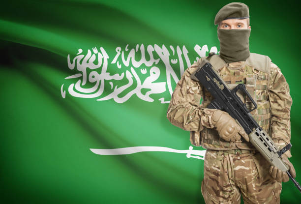 Soldier holding machine gun with flag on background series - Saudi Arabia stock photo