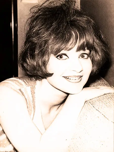 Vintage black and white portrait of a young woman from the sixties smiling at camera.