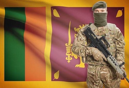 Soldier holding machine gun with national flag on background - Sri Lanka