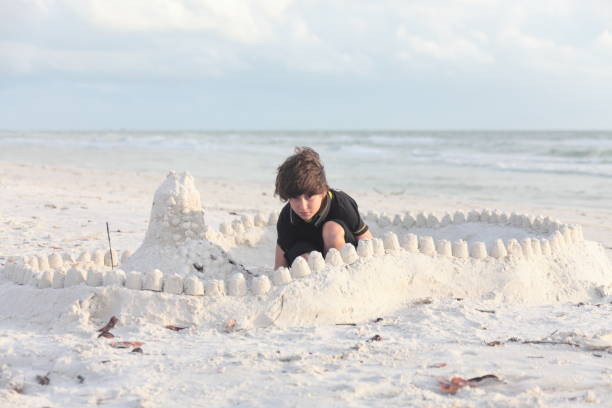 istock Boy at the beach builds sandcastle. 676037442