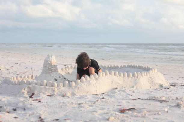 istock Boy at the beach builds sandcastle. 676037896
