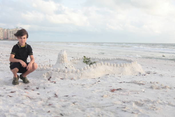 istock Boy at the beach builds sandcastle. 676037898
