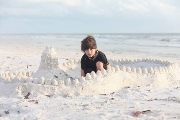 istock Boy at the beach builds sandcastle. 676038110