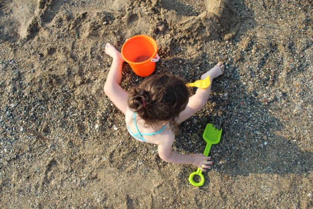 Baby girl playing in the sand with her pail and shovel,summer concept