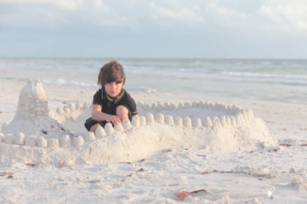 istock Boy at the beach builds sandcastle. 676045628