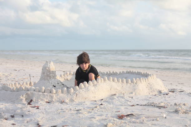 istock Boy at the beach builds sandcastle. 676045666