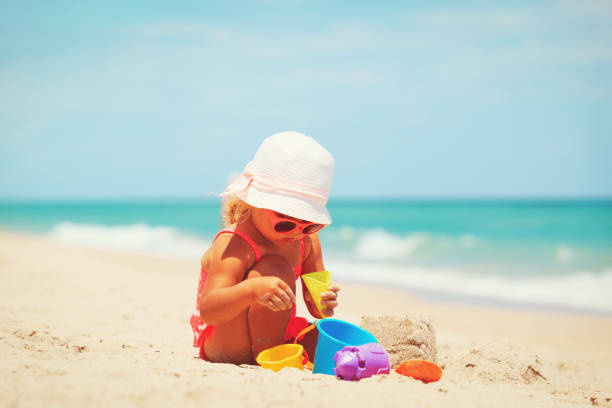 istock cute little girl play with sand on beach 676046238