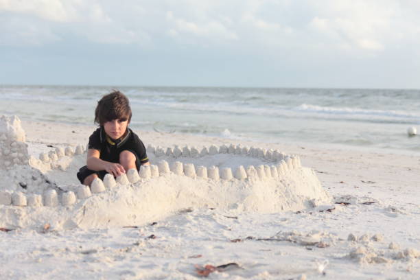 istock Boy at the beach builds sandcastle. 676046506