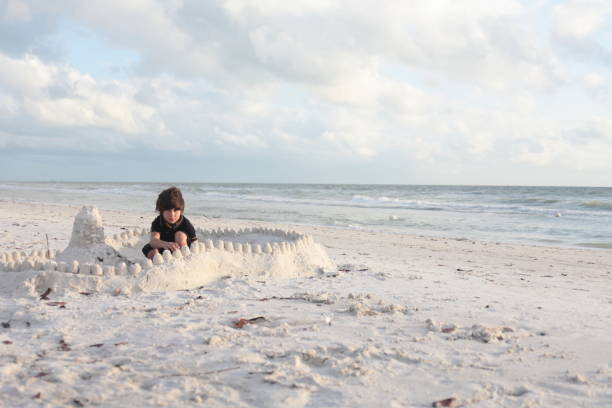 istock Boy at the beach builds sandcastle. 676046512