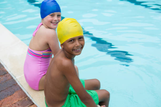 istock Smiling kids sitting near poolside 676053994