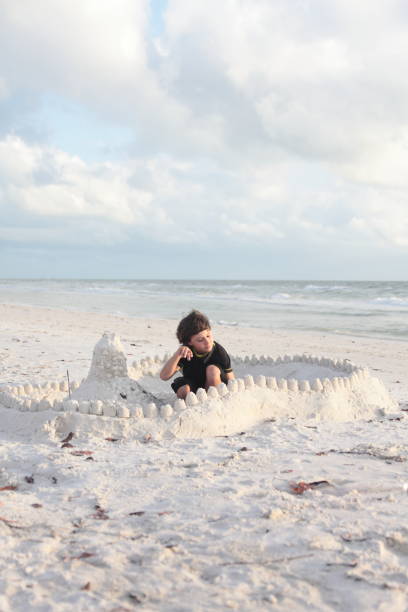 istock Boy at the beach builds sandcastle. 676056240