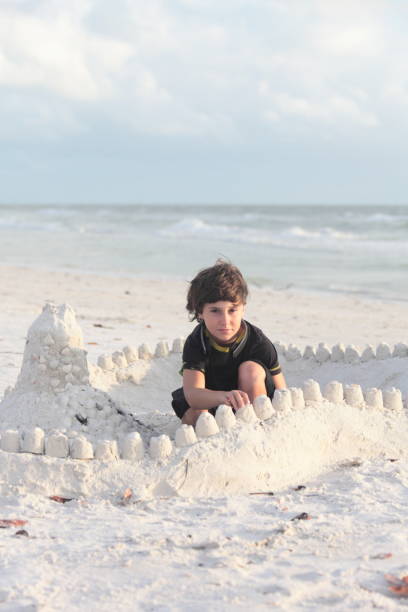 istock Boy at the beach builds sandcastle. 676056382