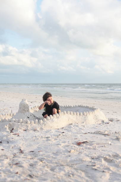 istock Boy at the beach builds sandcastle. 676056388