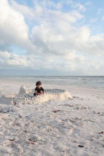 istock Boy at the beach builds sandcastle. 676056410